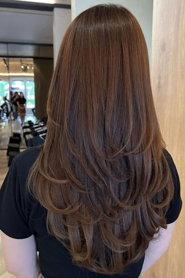Layered long brown hair with a smooth, glossy finish in a salon
